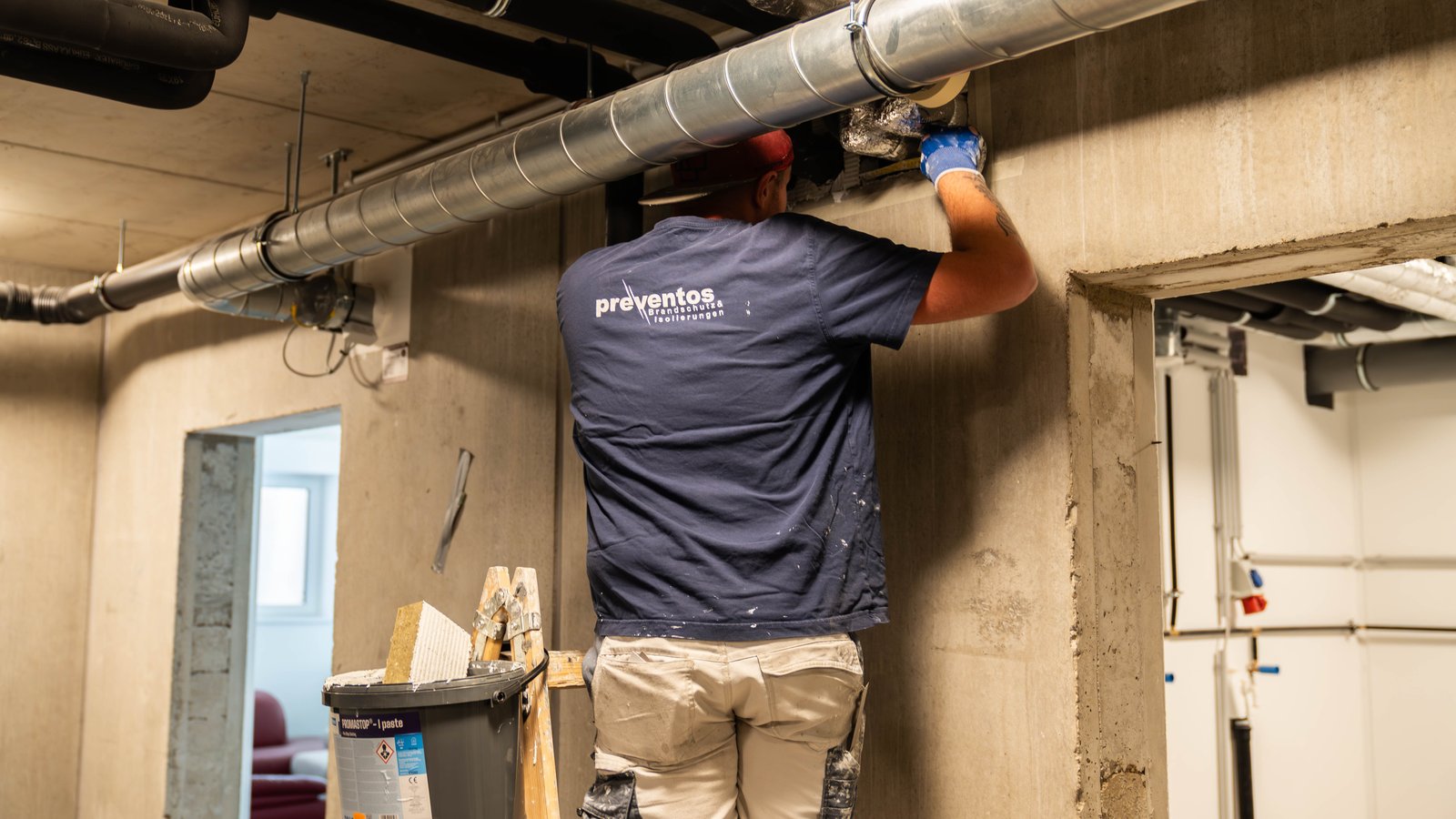 Monteur von Preventos Brandschutz isoliert eine Lüftungsleitung im Technikgang