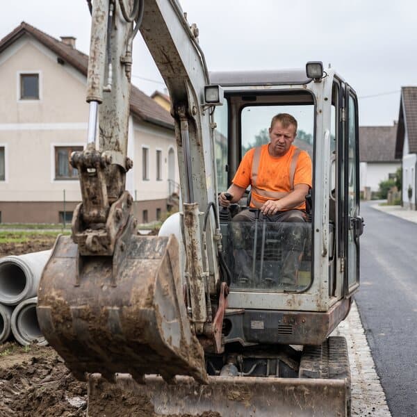 Baggerfahrer hebt einen Graben für den Kanal in einer Wohnstraße aus