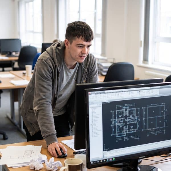Lehrling zeichnet einen Grundriss am CAD-Arbeitsplatz