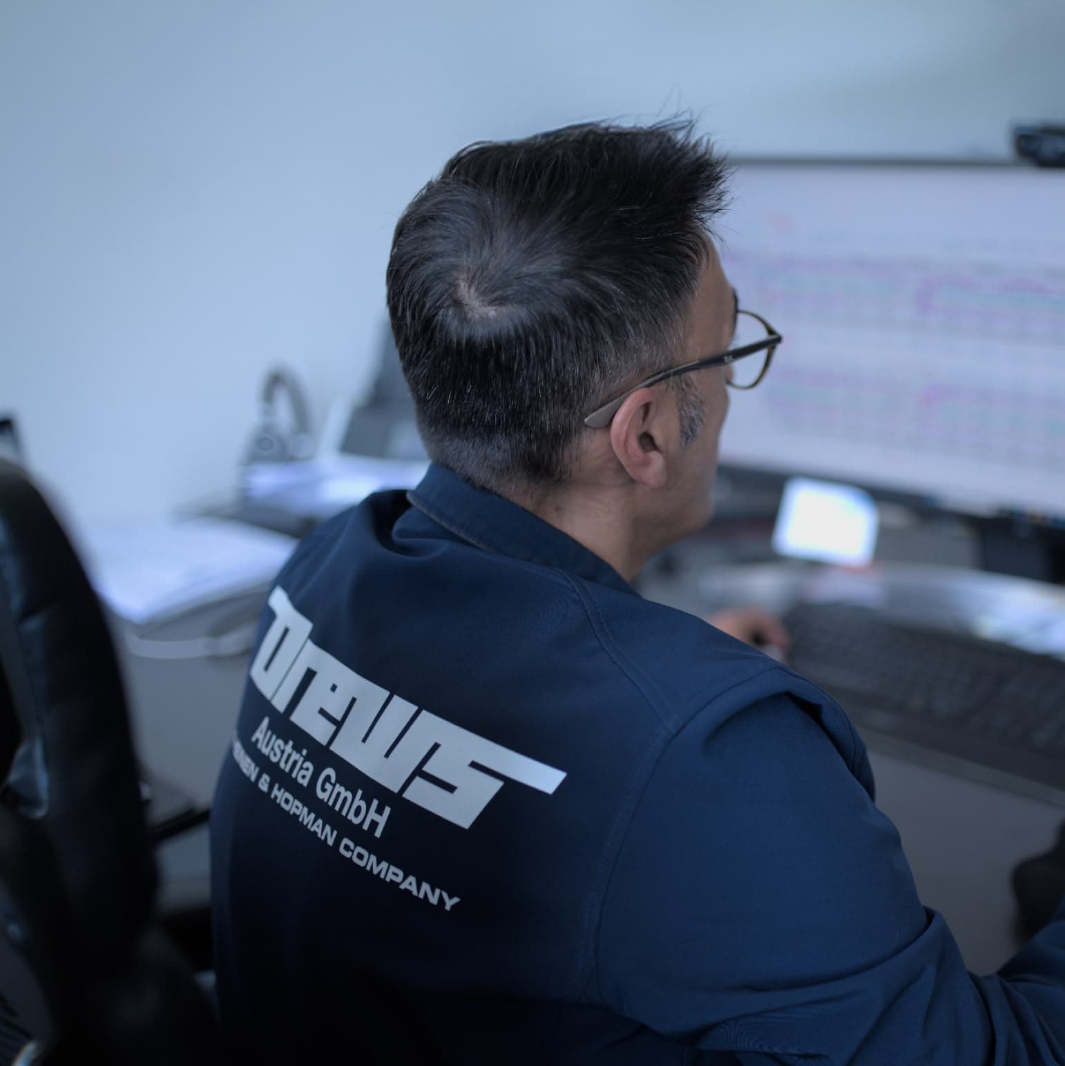 Mitarbeiter von Drews Austria in Arbeitskleidung am Bildschirm im Büro