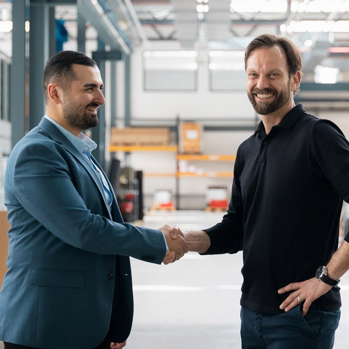 Yunus Akkaya gibt einem Betriebsinhaber in einer Werkshalle die Hand