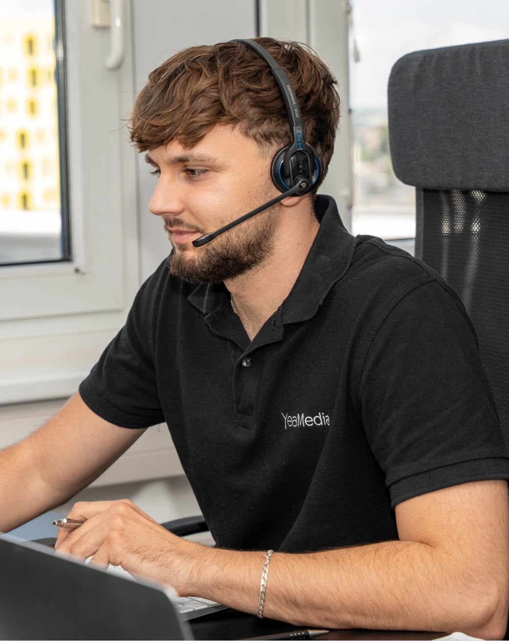 Mitarbeiter mit Headset am Schreibtisch im Telefonat
